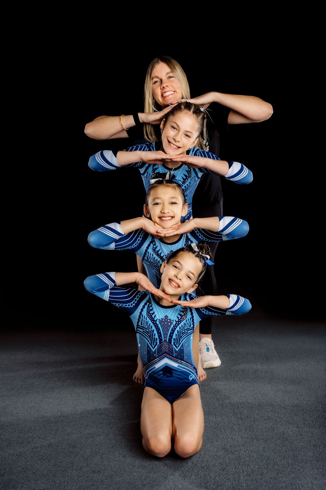 A Lake Point coach and three gymnasts stacked in a playful pose