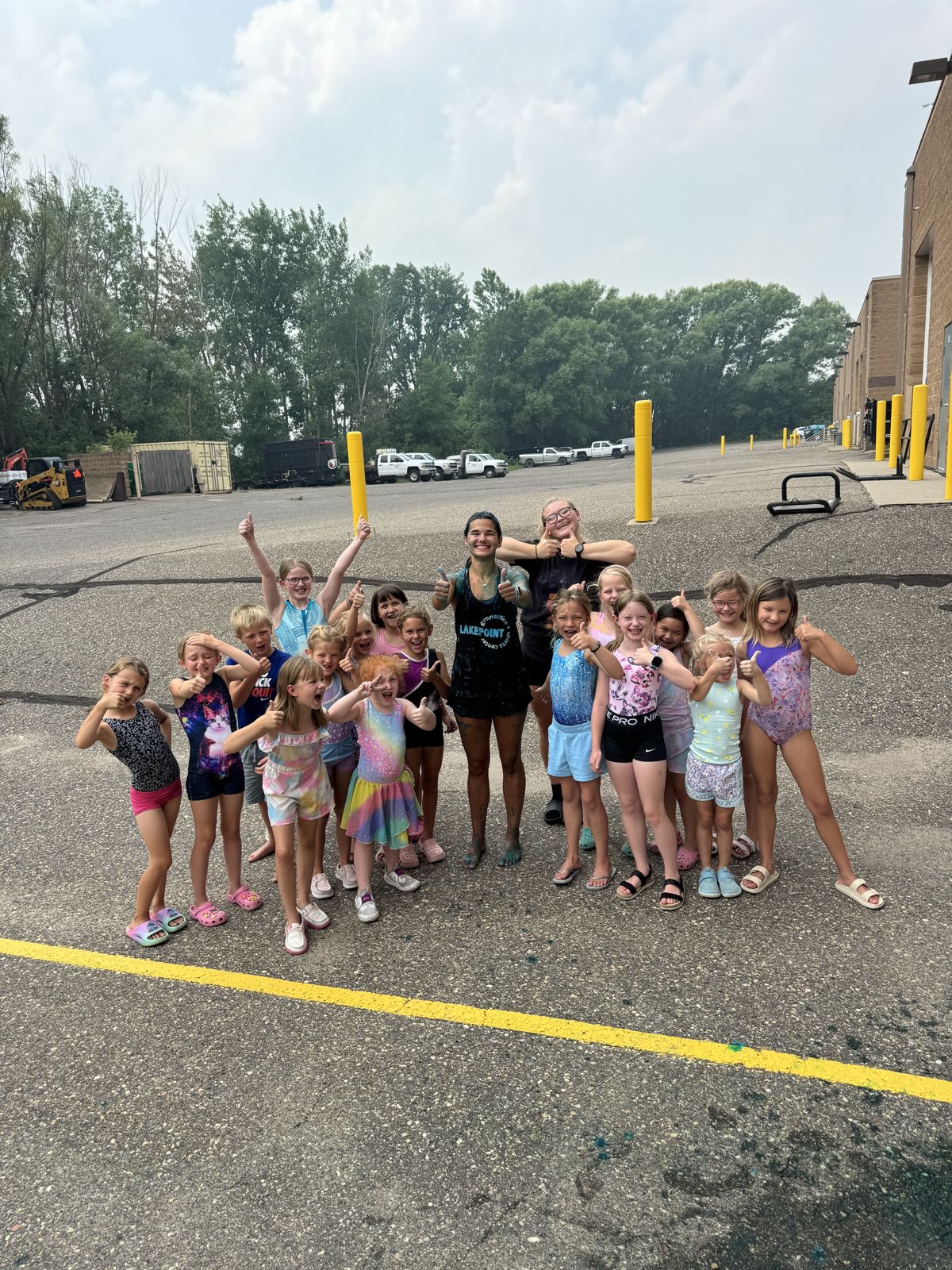 Summer campers giving a thumbs up outside the gym