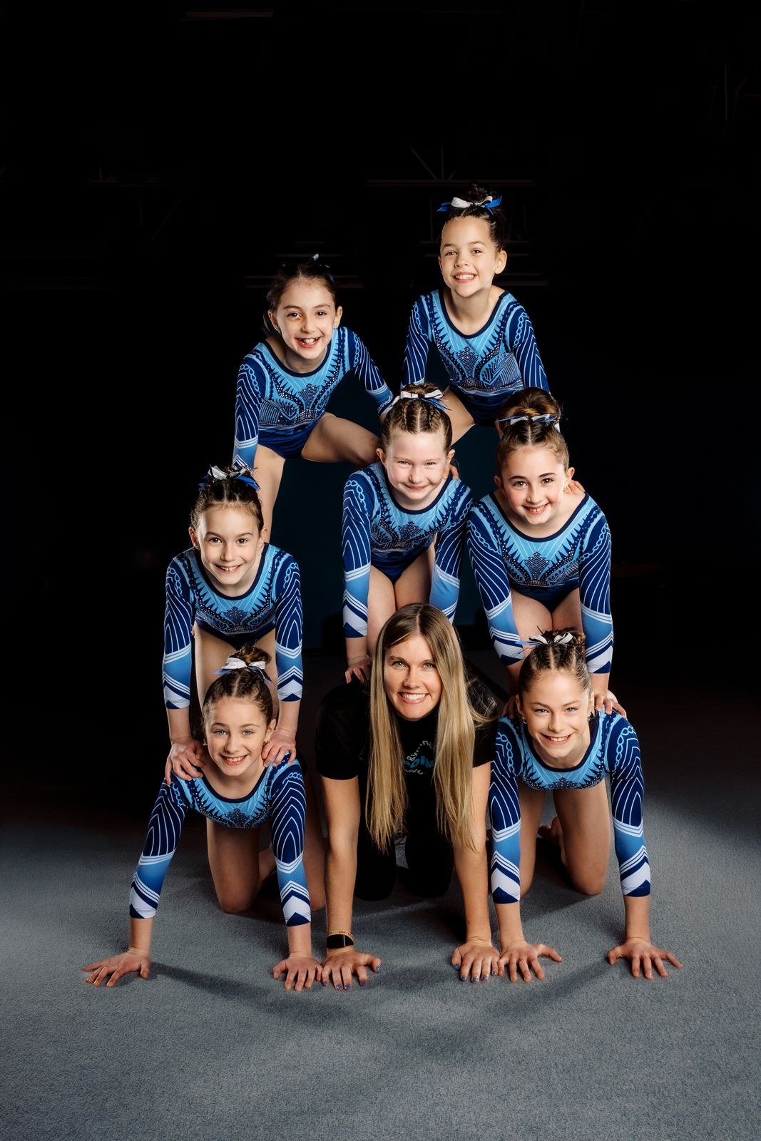 Lake Point team gymnasts in a pyramid with their coach